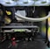 Inside view of a computer case showcasing a sophisticated gaming setup. Visible components include a GeForce RTX graphics card illuminated with green lighting, an ASUS motherboard, cooling fans with LED lighting, and a liquid cooling system with white tubes. Cables are neatly organized, and overall, the hardware suggests a high-performance machine.